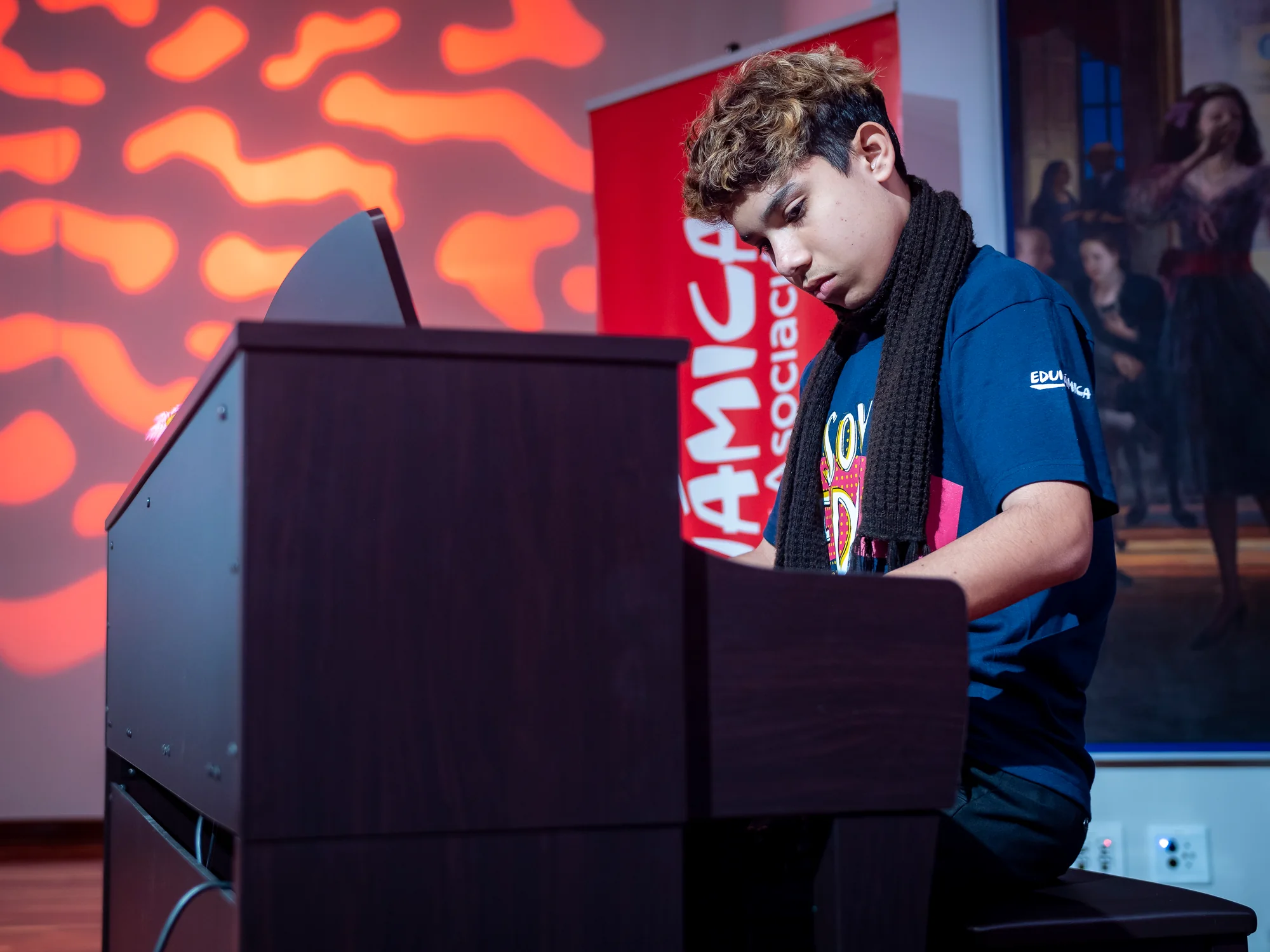 Joven de Edunámica tocando piano en tarima durante un interludio musical del evento