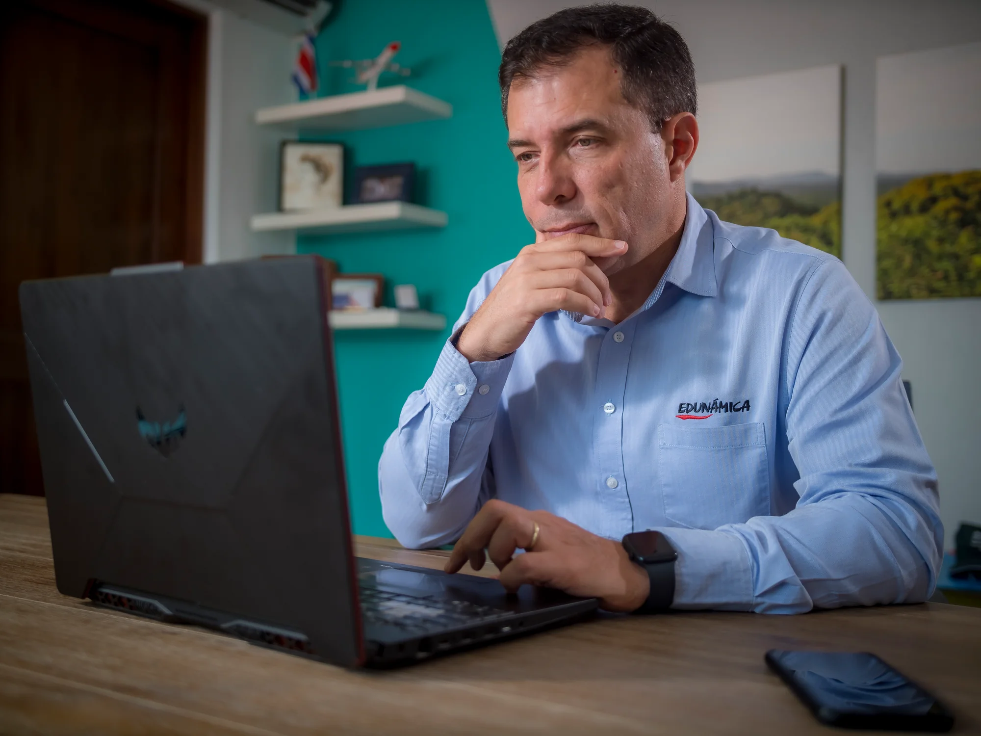 Retrato institucional de un colaborador de Edunámica con camisa de la organización, trabajando en su laptop