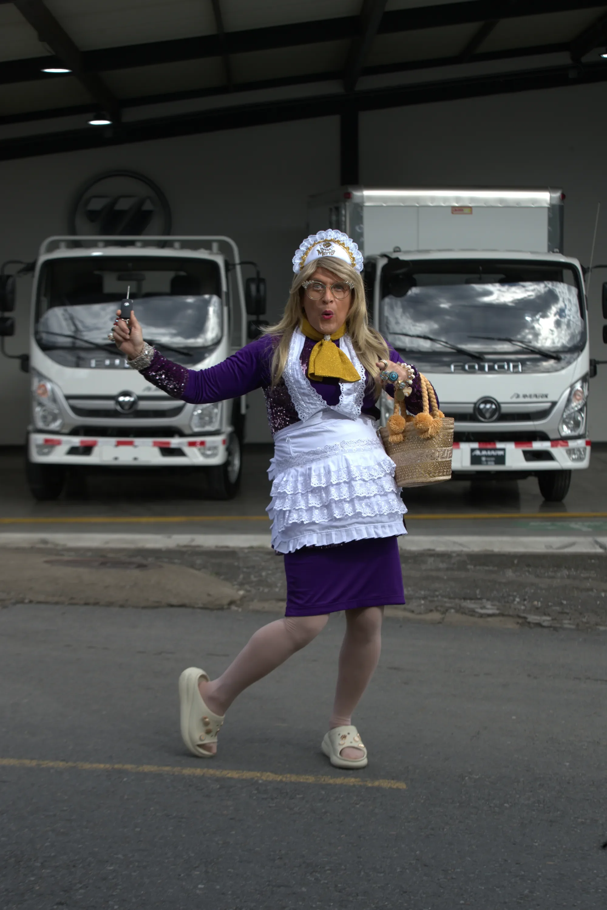 Doña Merry sostiene las llaves frente a dos camiones Foton Aumark en el concesionario