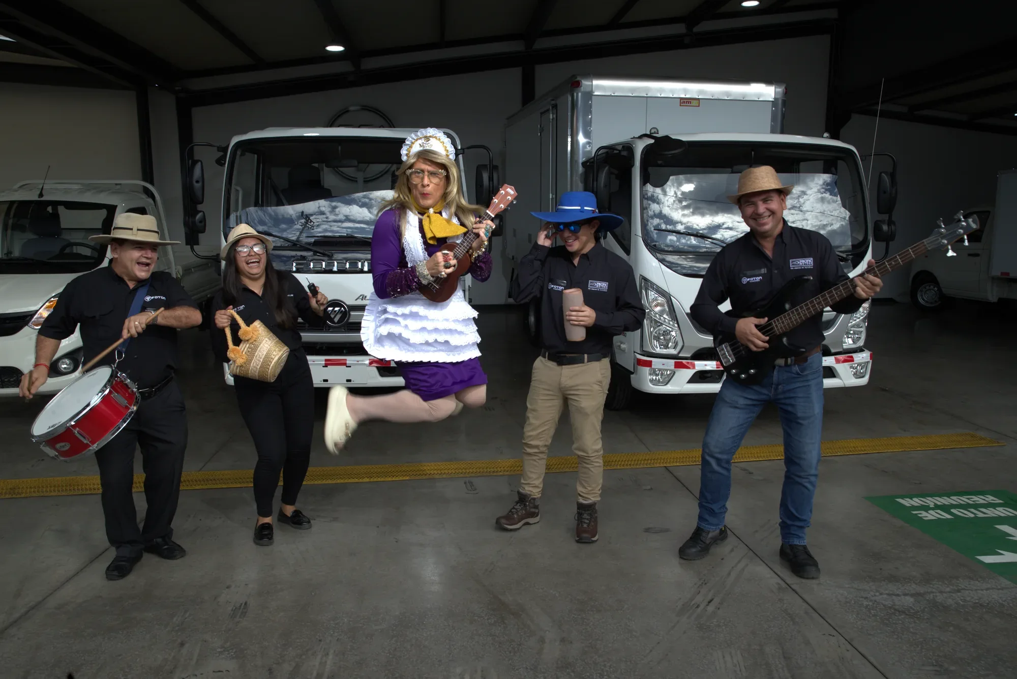 Doña Merry salta con ukulele junto al equipo de Pacific Motors frente a los camiones Foton