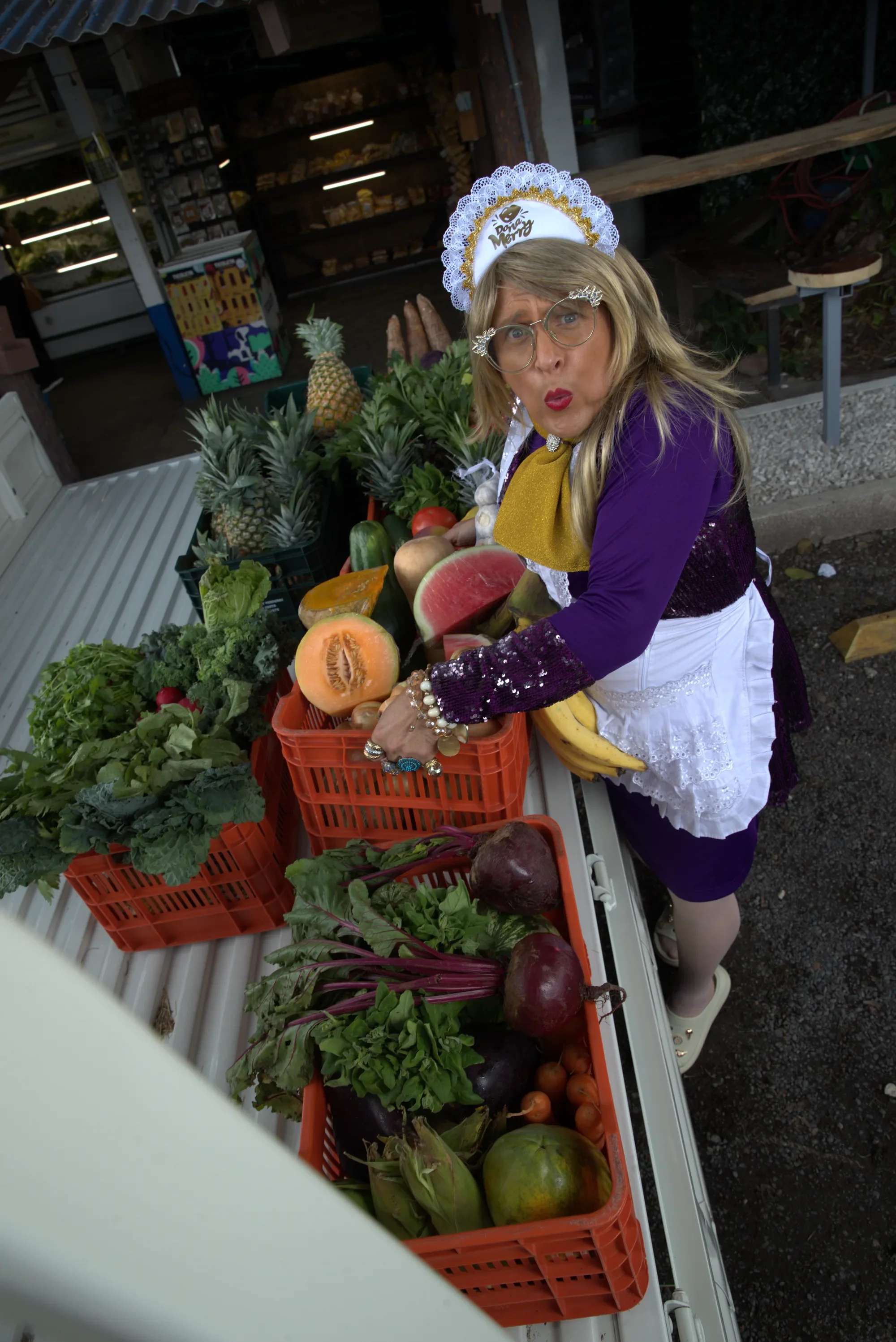 Doña Merry entre cajas de frutas y verduras en una feria del agricultor